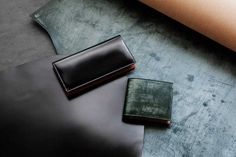 Two leather wallets on a textured surface with leather pieces.